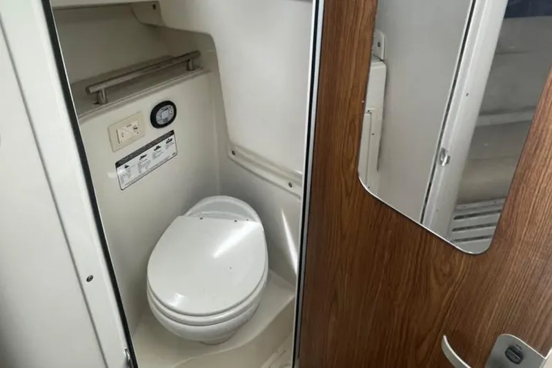 Slide: The Image of Compact bathroom inside 2020 Sailfish 270 WAC boat, featuring a modern toilet and wooden door. - 26