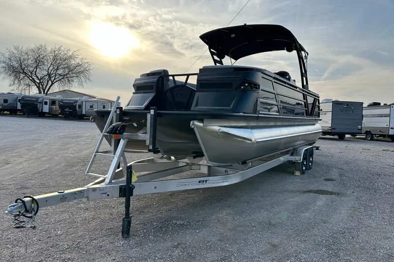 Slide: The Image of 2024 Veranda VX 25 DCVL pontoon boat on trailer, parked outdoors at sunset. - 2