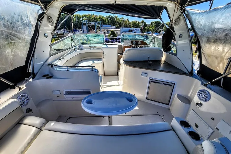 The Image of 2007 Rinker 320 Express Cruiser interior with seating, table, and helm in a marina setting. - 0