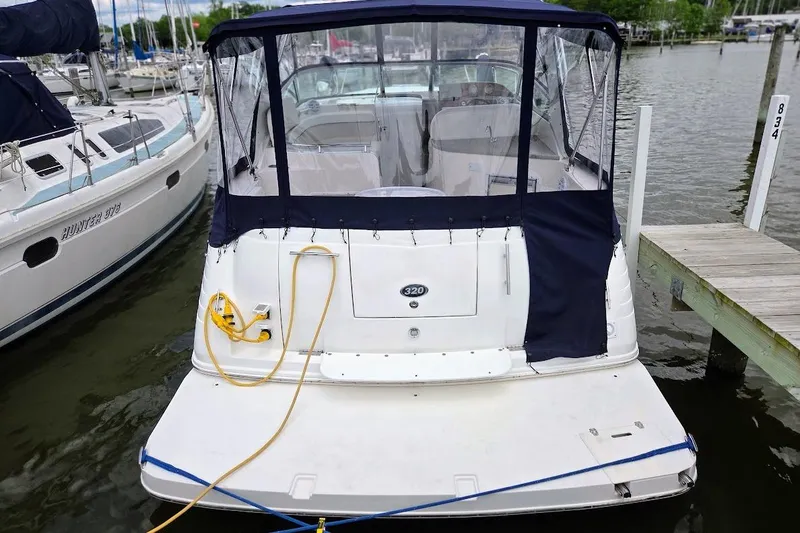 Slide: The Image of 2007 Rinker 320 Express Cruiser docked at marina, rear view with canopy and power cable. - 7