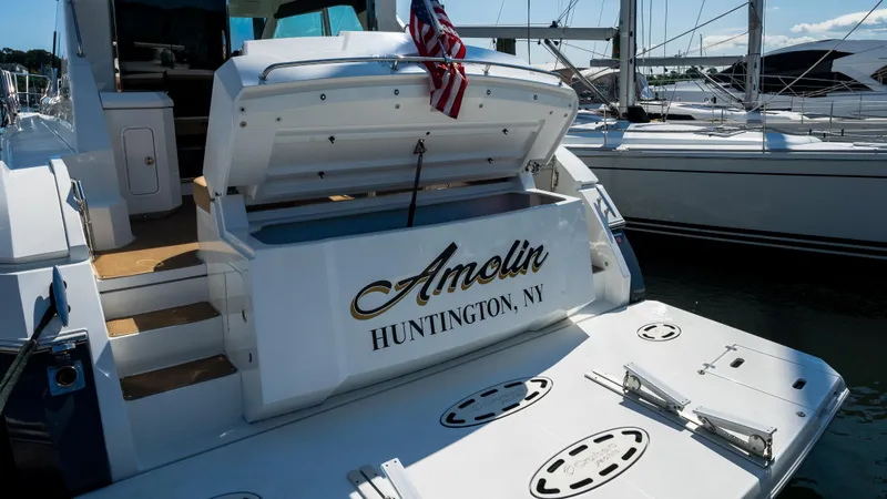 Slide: The Image of 2013 Cruisers Yachts 48 Cantius docked, featuring open storage and American flag. - 11