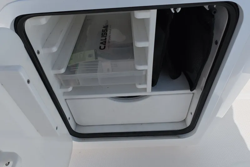 Slide: The Image of Storage compartment on 2023 Invincible 33 Catamaran, featuring organized shelves and a Calissa tackle box. - 30