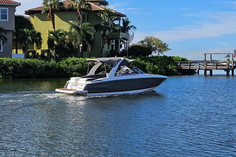 Slide: The Image of 2010 Regal 2700 ES Bowrider cruising near waterfront homes and lush greenery. - 46