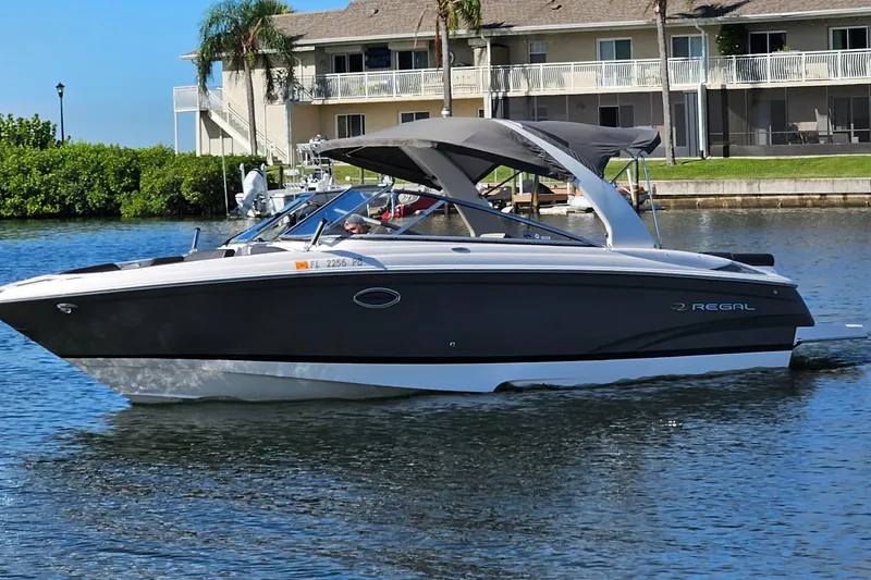 Slide: The Image of 2010 Regal 2700 ES Bowrider boat cruising on a sunny day near waterfront homes. - 55