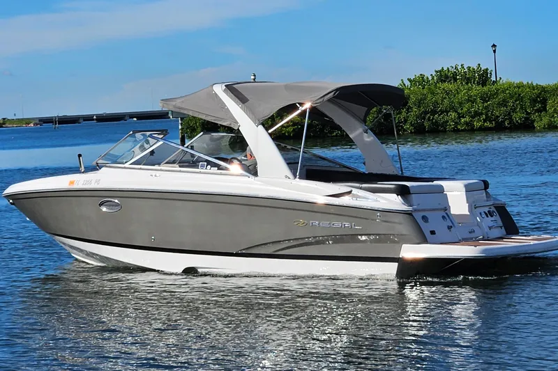 Slide: The Image of 2010 Regal 2700 ES Bowrider cruising on a sunny day, featuring sleek design and canopy. - 58