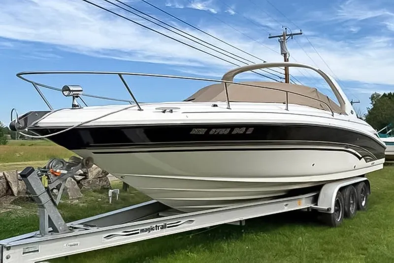 The Image of 2001 Sea Ray 290 Sun Sport boat on trailer, parked outdoors under blue sky. - 0