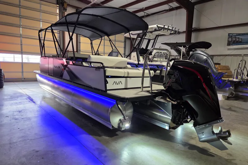 Slide: The Image of 2026 Avalon Platinum LSZ 2385 Entertainer pontoon boat in a showroom with blue LED lights. - 13