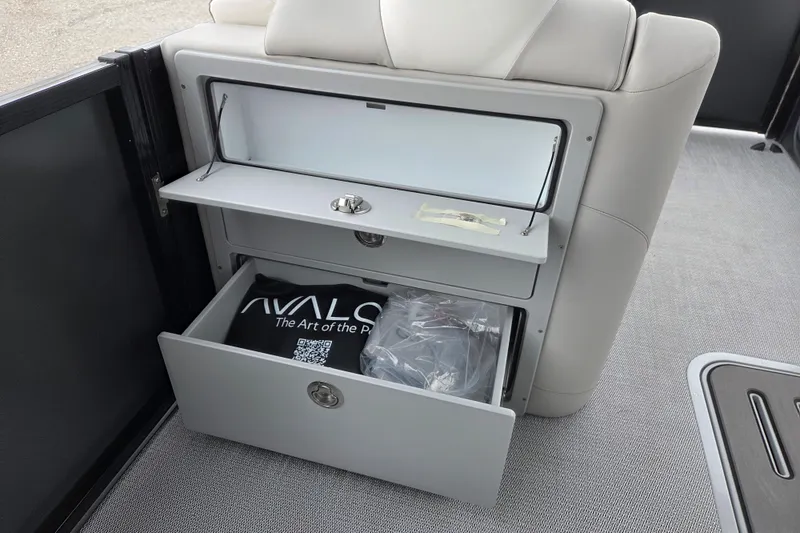 Slide: The Image of 2026 Avalon Platinum LSZ 2385 Entertainer boat storage compartments with branded items inside. - 7