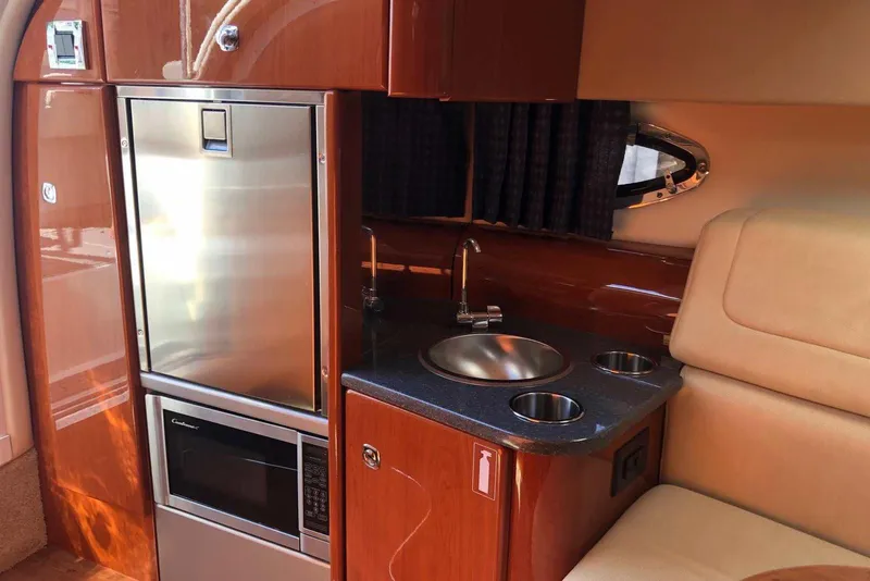 Slide: The Image of 2012 Formula 310 Sun Sport interior with kitchenette, featuring stainless steel appliances and wood finish. - 27