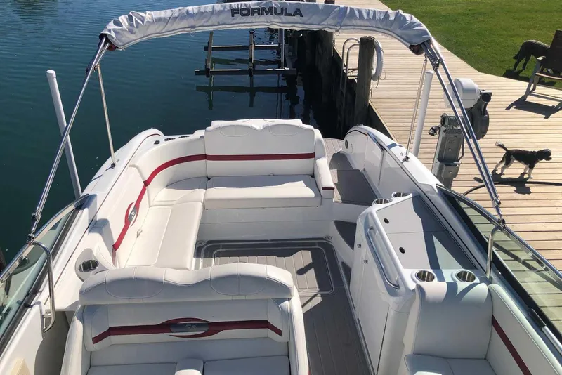 Slide: The Image of 2012 Formula 310 Sun Sport boat interior with white seating and red accents, docked by a wooden pier. - 7