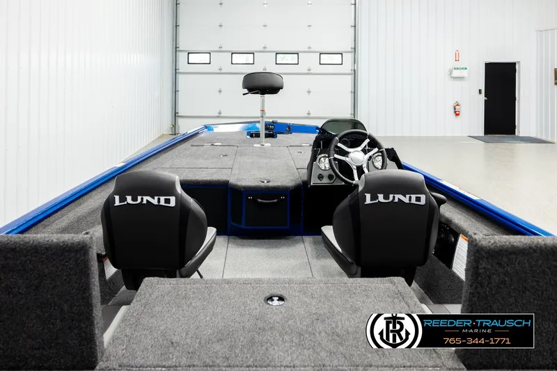 Slide: The Image of 2026 Lund 1875 Renegade boat interior with dual seats and steering console in a showroom. - 11