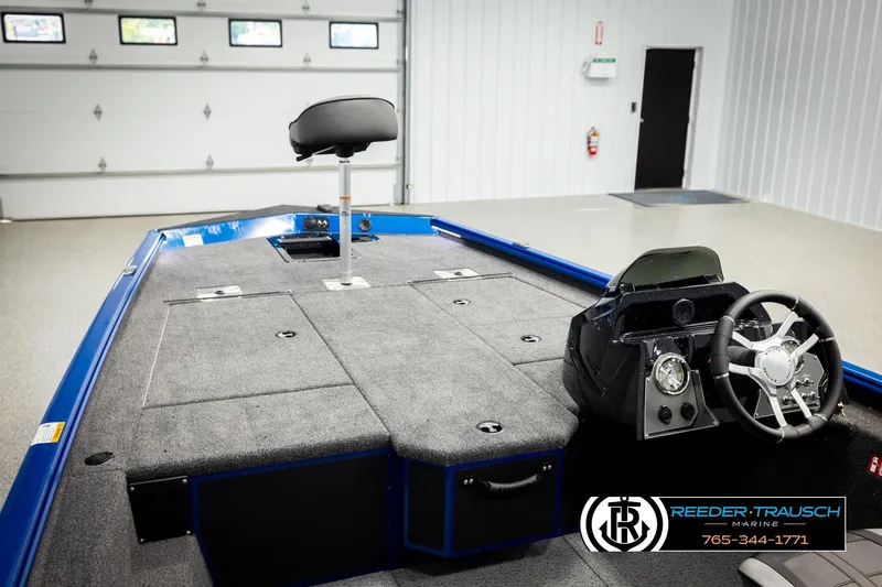 Slide: The Image of 2026 Lund 1875 Renegade boat interior with steering wheel and seating in a garage. - 21