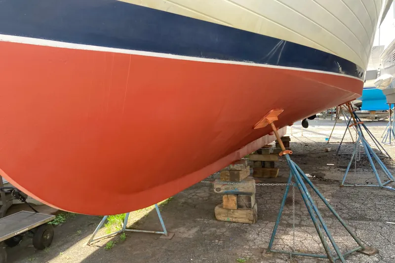 Slide: The Image of 1988 Grand Banks 42 Classic boat hull on stands, showcasing red and blue paint. - 37
