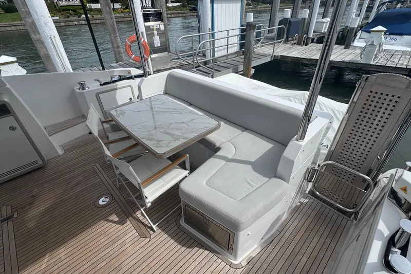 Slide: The Image of Luxurious seating area on 2021 Azimut 50 Flybridge yacht with marble table and cushioned bench. - 12