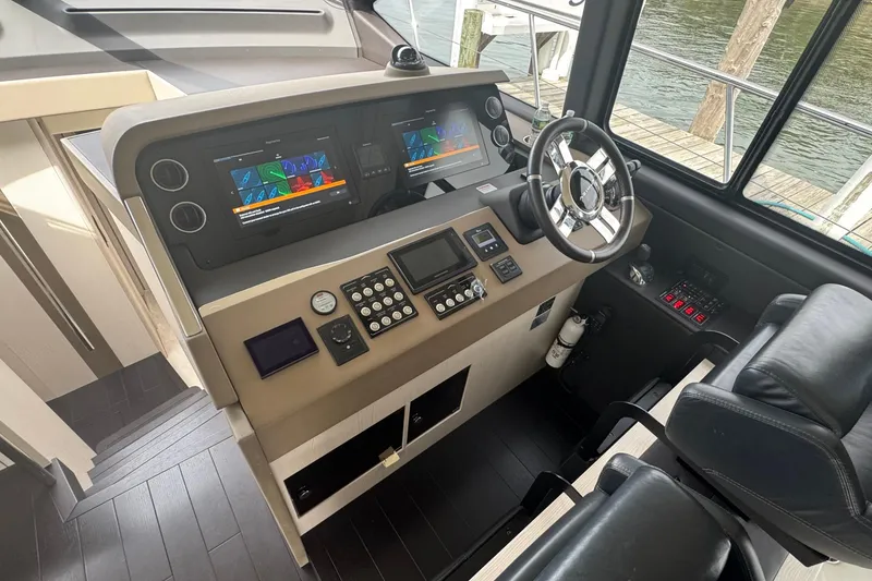 Slide: The Image of 2021 Azimut 50 Flybridge helm with dual displays, steering wheel, and control panel. - 26