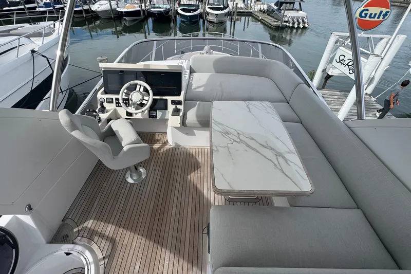 Slide: The Image of Flybridge of 2021 Azimut 50, featuring helm, marble table, and plush seating at marina. - 57
