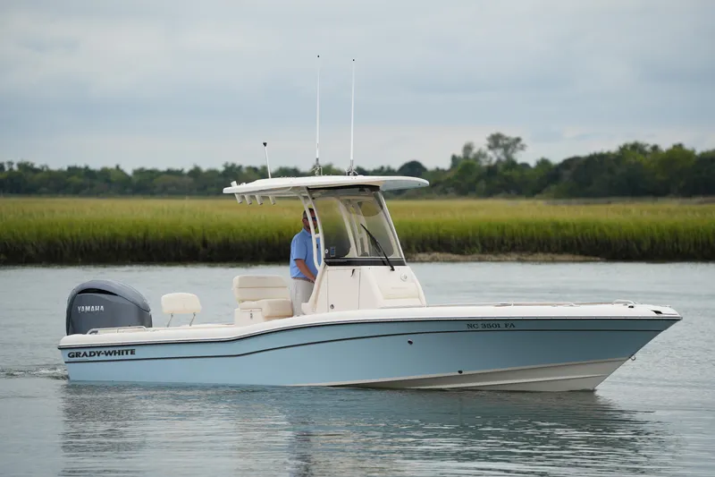 Slide: The Image of 2023 Grady-White 251 Coastal Explorer boat on calm water with lush green shoreline. - 10