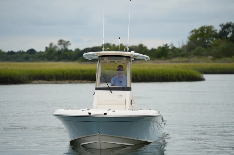 Slide: The Image of 2023 Grady-White 251 Coastal Explorer boat on calm water, with lush greenery in the background. - 15