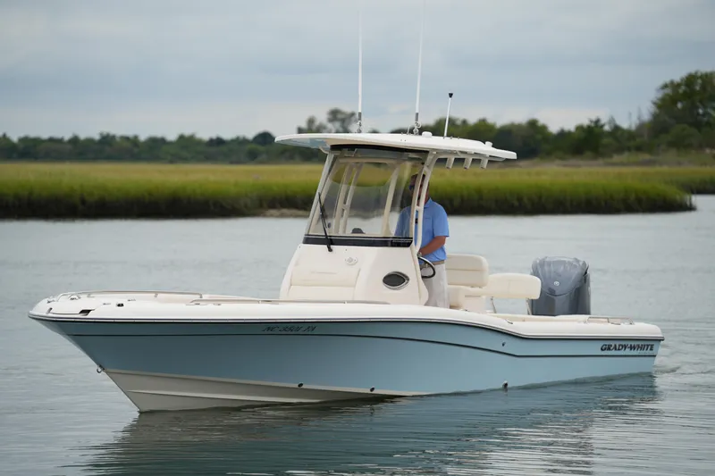 Slide: The Image of 2023 Grady-White 251 Coastal Explorer boat on calm water, with lush greenery in the background. - 17