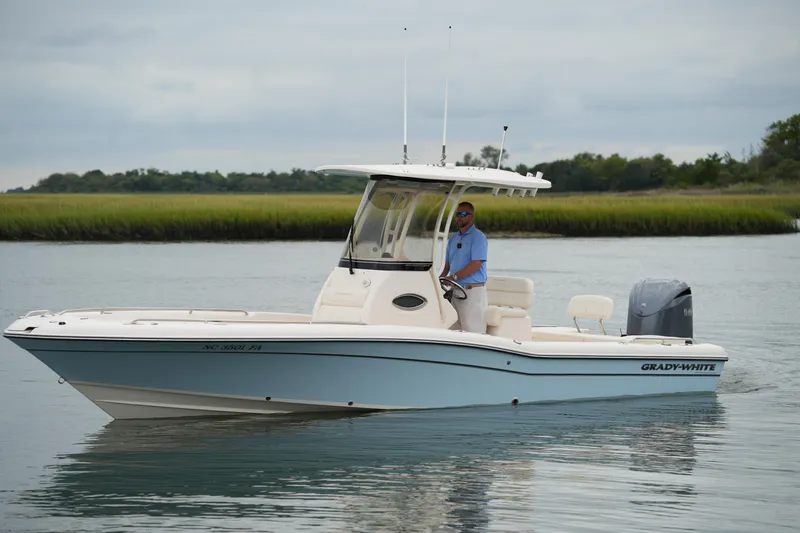 Slide: The Image of 2023 Grady-White 251 Coastal Explorer boat on calm water with a person at the helm. - 18