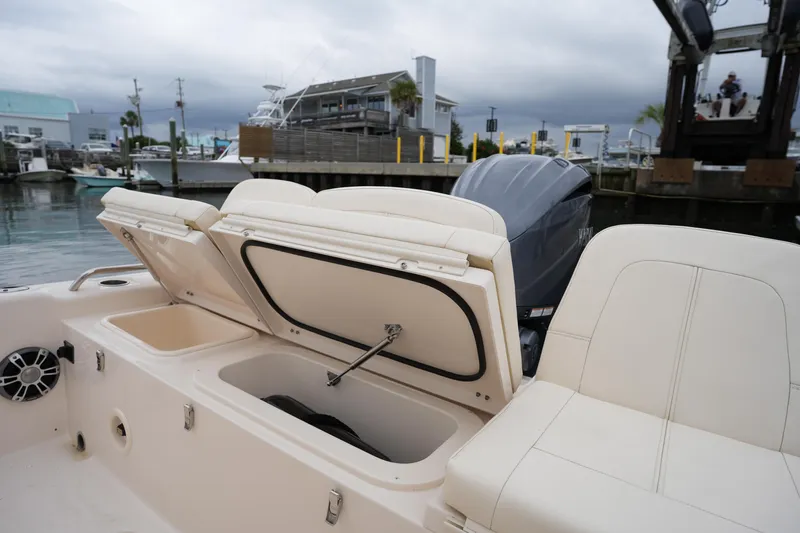 Slide: The Image of 2023 Grady-White 251 Coastal Explorer boat with open storage compartments at a marina. - 23