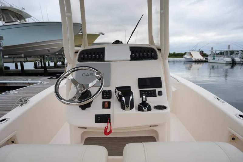 Slide: The Image of 2023 Grady-White 251 Coastal Explorer boat helm with steering wheel and controls at marina. - 29