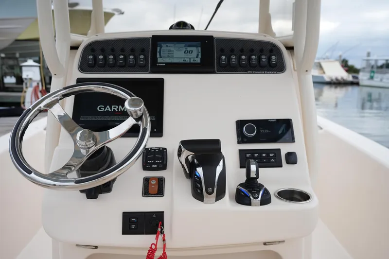 Slide: The Image of 2023 Grady-White 251 Coastal Explorer boat dashboard with steering wheel and navigation controls. - 30