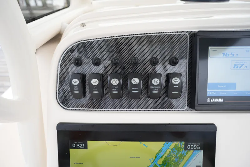 Slide: The Image of 2023 Grady-White 251 Coastal Explorer dashboard with control switches and navigation display. - 33