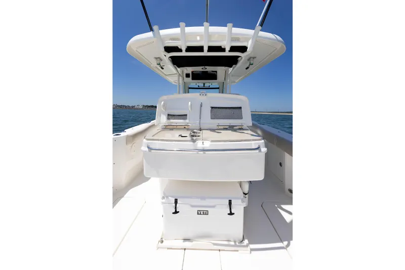 Slide: The Image of 2016 Boston Whaler 330 Outrage boat interior with Yeti cooler, under clear blue sky. - 13