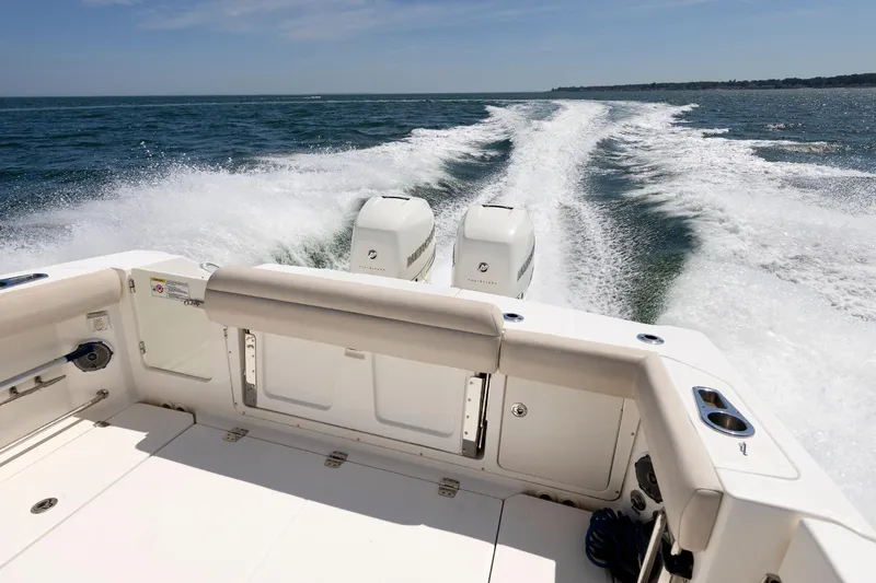 Slide: The Image of 2016 Boston Whaler 330 Outrage cruising on open water, rear view with twin engines. - 20
