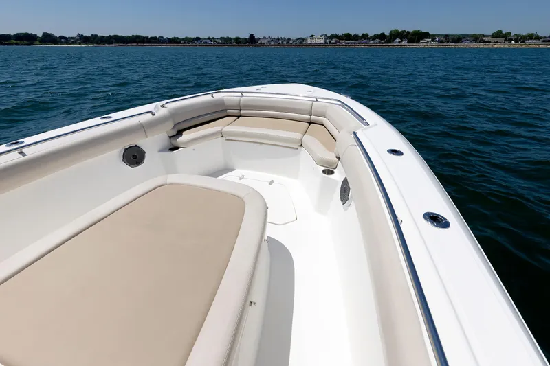 Slide: The Image of 2016 Boston Whaler 330 Outrage boat interior with cushioned seating on calm water. - 6