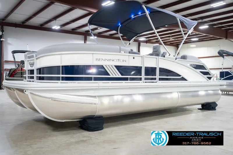 Slide: The Image of 2026 Bennington 22 MSB pontoon boat in showroom with canopy and sleek design. - 2