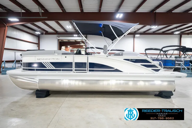 Slide: The Image of 2026 Bennington 22 MSB pontoon boat in showroom, featuring sleek design and canopy. - 9