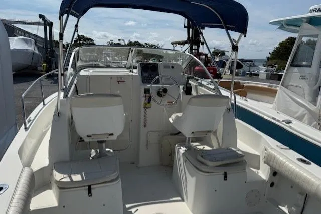 Slide: The Image of 2004 Glastron 213 WA boat interior with seating and steering wheel, docked under blue canopy. - 4
