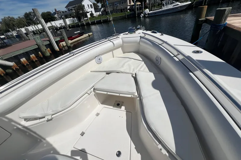Slide: The Image of 2004 Robalo R260 Center Console boat interior with white cushioned seating at a dock. - 9