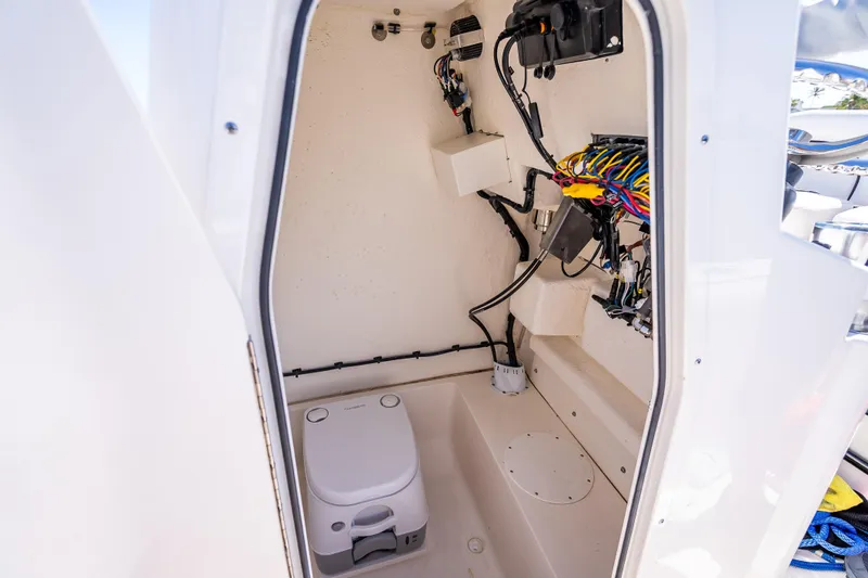 Slide: The Image of Interior of 2026 Sea Born LX21 Center Console boat, featuring wiring and a portable toilet. - 51