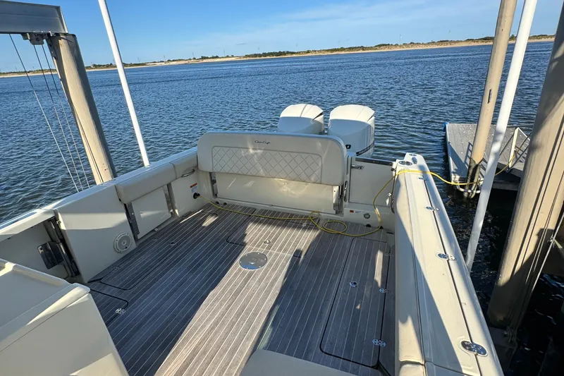 Slide: The Image of 2018 Chris-Craft Calypso 30 boat docked on calm water, showcasing spacious deck. - 11