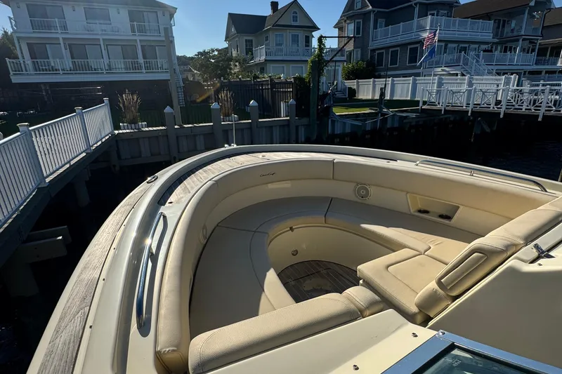 Slide: The Image of 2018 Chris-Craft Calypso 30 boat with beige seating, docked near waterfront homes. - 14