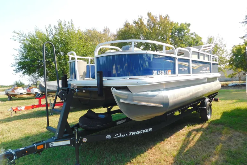 The Image of 2025 Sun Tracker Bass Buggy pontoon boat on trailer, parked on grass. - 0