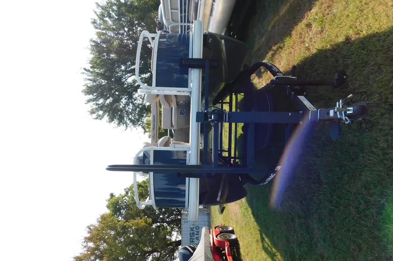 Slide: The Image of 2025 Sun Tracker Bass Buggy pontoon boat on trailer, parked on grass. - 4