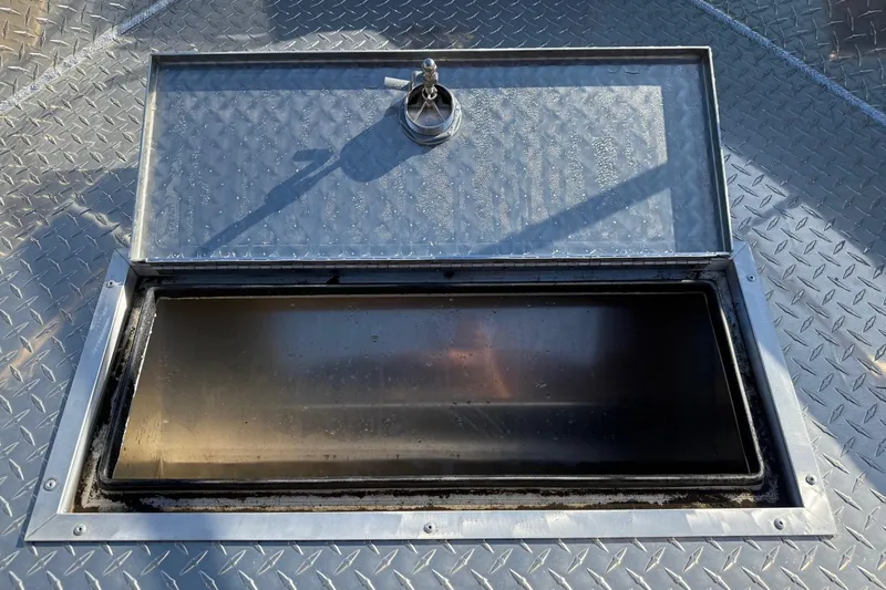 Slide: The Image of Open storage compartment on 2025 Thunder Jet 24 Alexis Pro boat with diamond plate surface. - 7