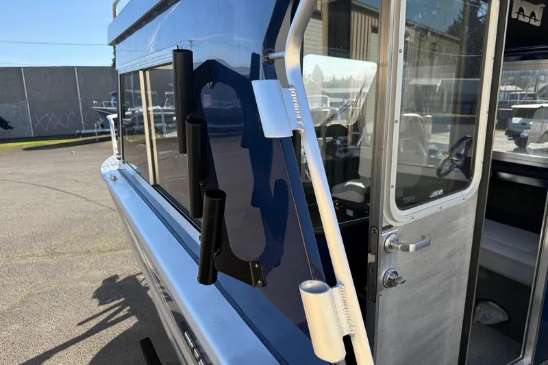 Slide: The Image of 2025 Thunder Jet 24 Alexis Pro boat exterior with rod holders and cabin door. - 8