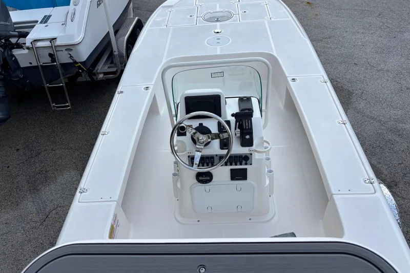 Slide: The Image of 2026 Spyder FX19 Vapor boat with steering console, parked on pavement. - 3