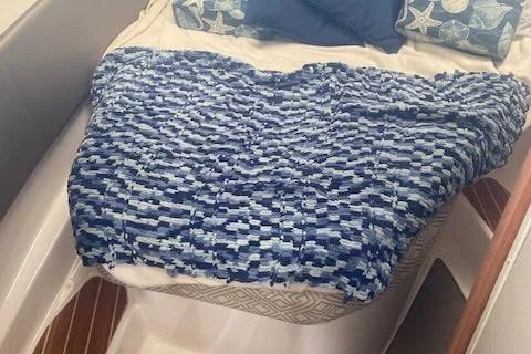 Slide: The Image of 2020 Cutwater C-32 C cabin interior with blue patterned blanket and pillows. - 20