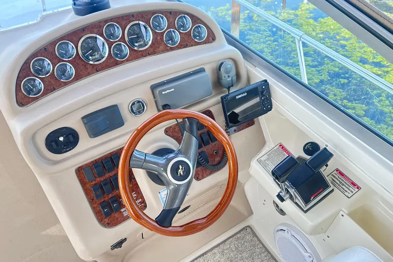 Slide: The Image of 2000 Sea Ray 290 Sundancer helm with wood-accented steering wheel and modern navigation instruments. - 8