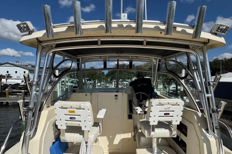 Slide: The Image of 2011 Parker 2510 XL Walkaround boat interior with helm and seating under a clear sky. - 2