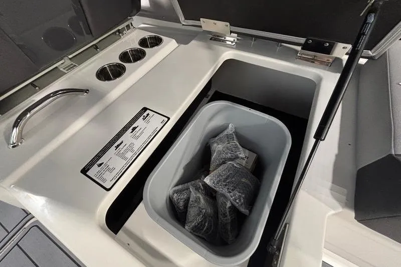 Slide: The Image of Cobalt R33 2026 boat storage compartment with cup holders and storage bin. - 23