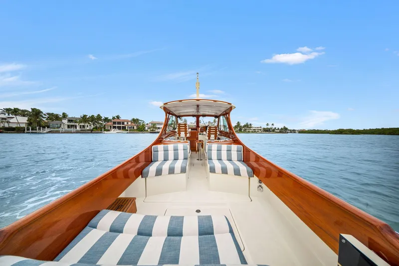 Slide: The Image of 2019 Hinckley Picnic Boat 34 on serene water, featuring elegant striped seating. - 2