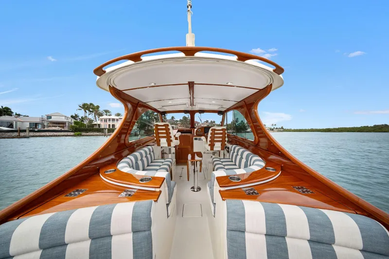 Slide: The Image of 2019 Hinckley Picnic Boat 34 with elegant wood finish and striped seating on calm water. - 4