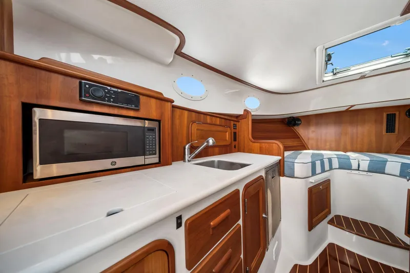 Slide: The Image of 2019 Hinckley Picnic Boat 34 interior with kitchenette, microwave, sink, and seating area. - 7